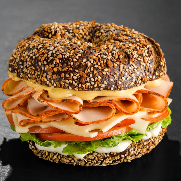 A Go Bagels everything bagel sandwich with turkey, cheese, lettuce, tomato, and sauces.