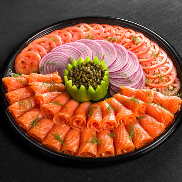 Go Bagels lox platter with sliced salmon, tomatoes, red onions, and capers in a lime.
