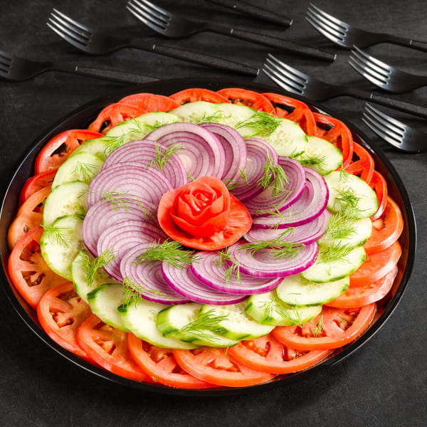 A platter of sliced tomatoes, cucumbers, and red onions with a tomato rose center.