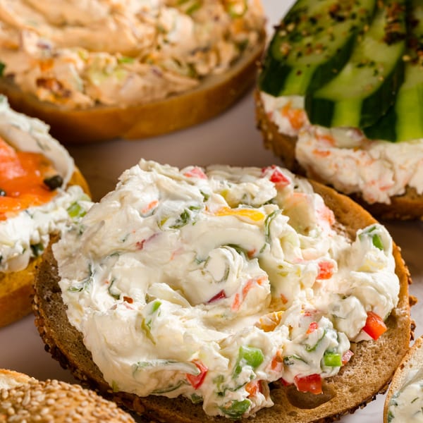Close-up of bagels with various cream cheese spreads, including vegetable, salmon, and cucumber.